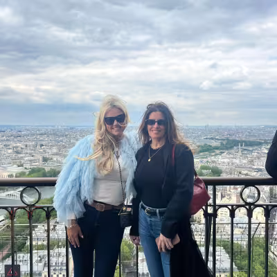 Two travelers on an Eiffel Tower viewing platform overlooking the Paris skyline