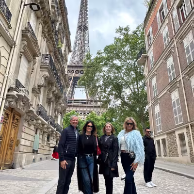 Friends posing on a cobblestone Paris street with the Eiffel Tower rising between Haussmann buildings