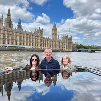 Family on a private boat ride on the Thames with the Houses of Parliament and Big Ben behind