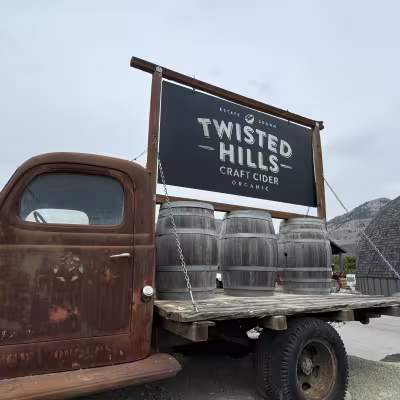 Rustic vintage truck displaying a Twisted Hills Craft Cider sign and wooden barrels