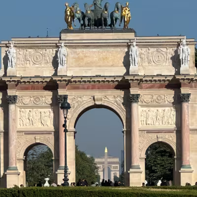 Triumphal arch in Paris with chariot statues and distant city landmarks framed beneath