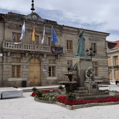 Stone town hall and statue in central plaza of a Galicia village
