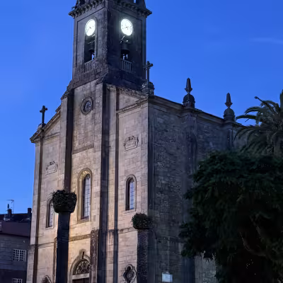 Illuminated church tower at blue hour in a Galician town square