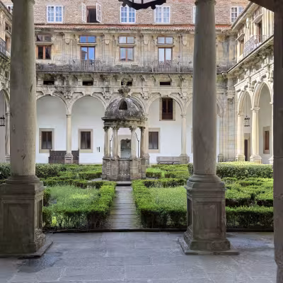 Historic cloister courtyard with stone well and manicured hedges in Santiago de Compostela