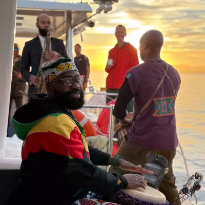 man playing drums on a yacht at sunrise