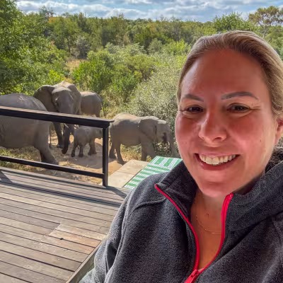 girl standing at pool in front of herd of elephants