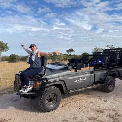 girl on safari vehicle with arms out