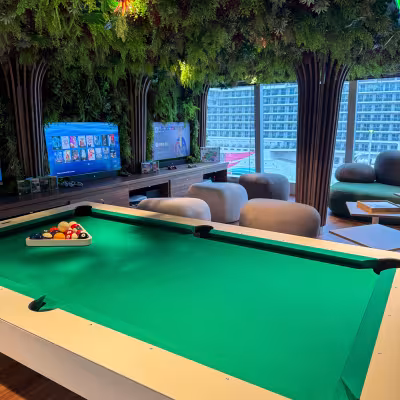 Explora Journeys indoor entertainment lounge with a pool table, gaming consoles, and living plant wall