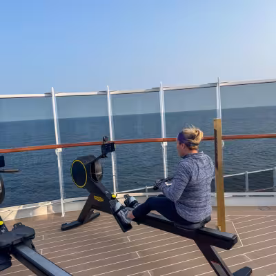 Guest rowing with ocean views at the outdoor Ocean Wellness fitness area aboard Explora Journeys