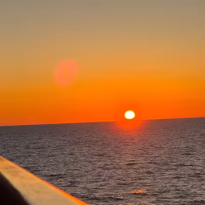 Sunset over the ocean viewed from the deck of an Explora Journeys cruise ship