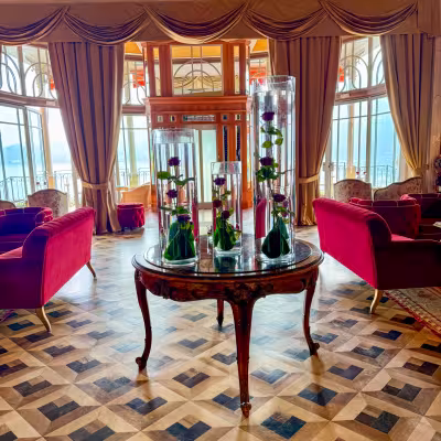 Grand Lake Como hotel salon with red velvet seating, floral displays, and lake views
