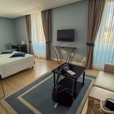 Elegant hotel suite with bedroom, sitting area, and city-view windows in Turin, Italy