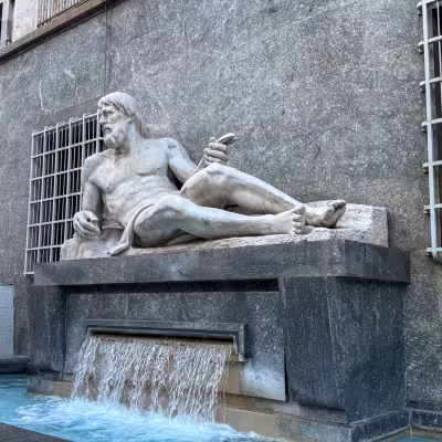 Marble reclining river-god statue above a cascading fountain in Naples, Italy.