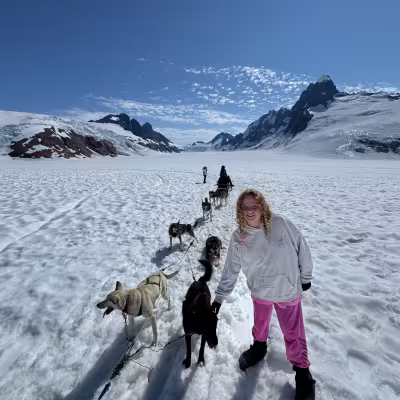 Teen posing with a sled dog team on the snowy glacier during a Juneau dog sledding tour