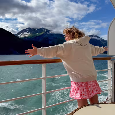 Teen enjoying the view from Regent Seven Seas Explorer's deck, cruising past Alaska's glacier-carved fjords