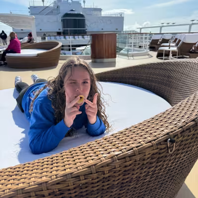 Teen relaxing poolside on Regent Seven Seas Explorer's sun deck during a scenic day at sea in Alaska