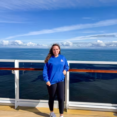 Teen posing on the outdoor deck of Regent Seven Seas Explorer with the open ocean behind her