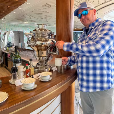 Dad pouring tea from a silver samovar at Regent Seven Seas Explorer's onboard bar