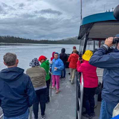 Passengers in rain gear watching for wildlife during a Sitka sea life cruise excursion