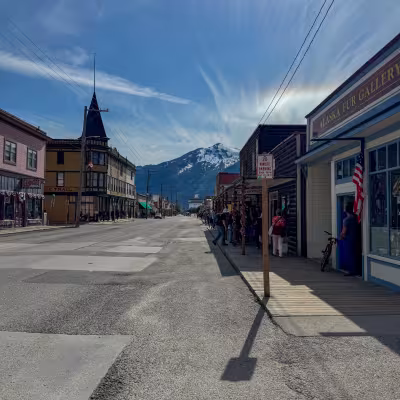 Historic Broadway Street storefronts in Skagway, Alaska, with snow-capped mountains in the distance