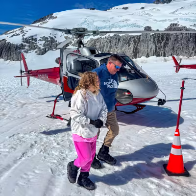 Father and daughter walking off the helicopter on a glacier landing pad above Juneau, Alaska