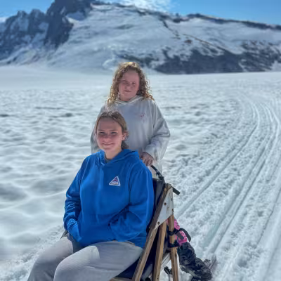 Teens riding a dog sled together on the glacier above Juneau, Alaska