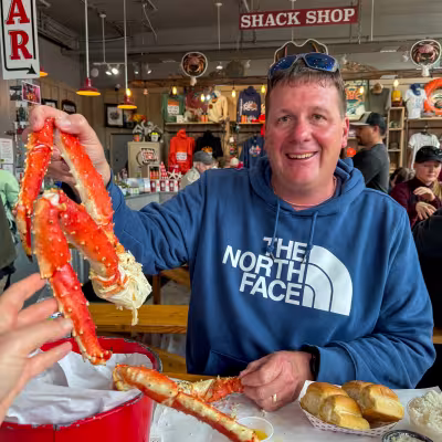 Dad holding up Alaska king crab legs at tracys crab shack feast in Juneau