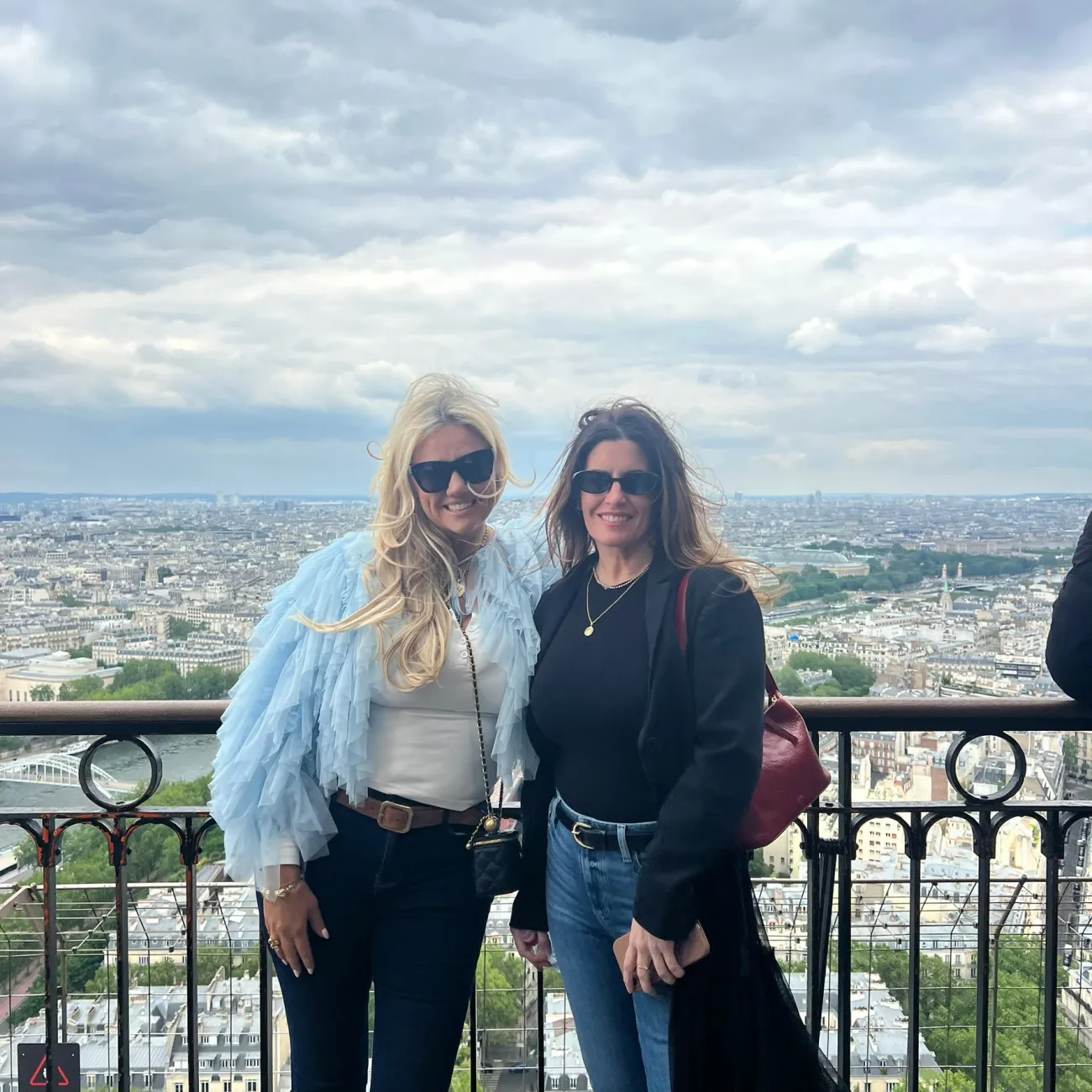 Two travelers on an Eiffel Tower viewing platform overlooking the Paris skyline