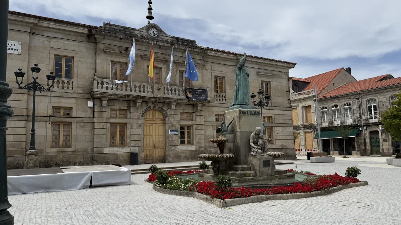 Stone town hall and statue in central plaza of a Galicia village